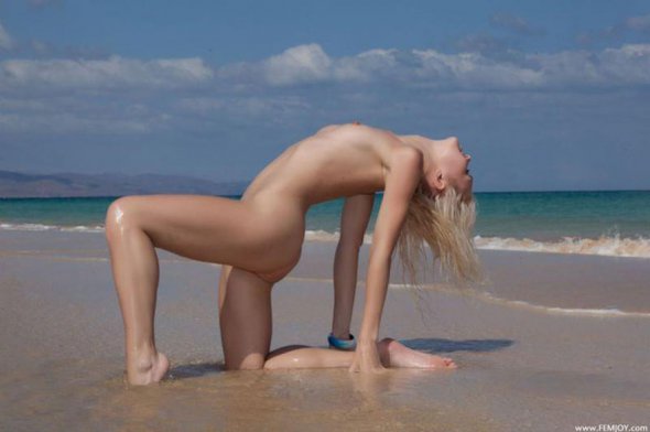 Голая блондинка с маленькой грудью эротично позирует на море