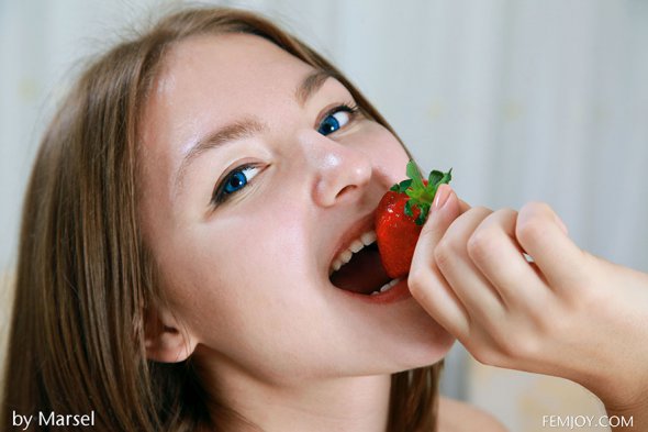 Юная девушка в красных чулочках ест клубнику