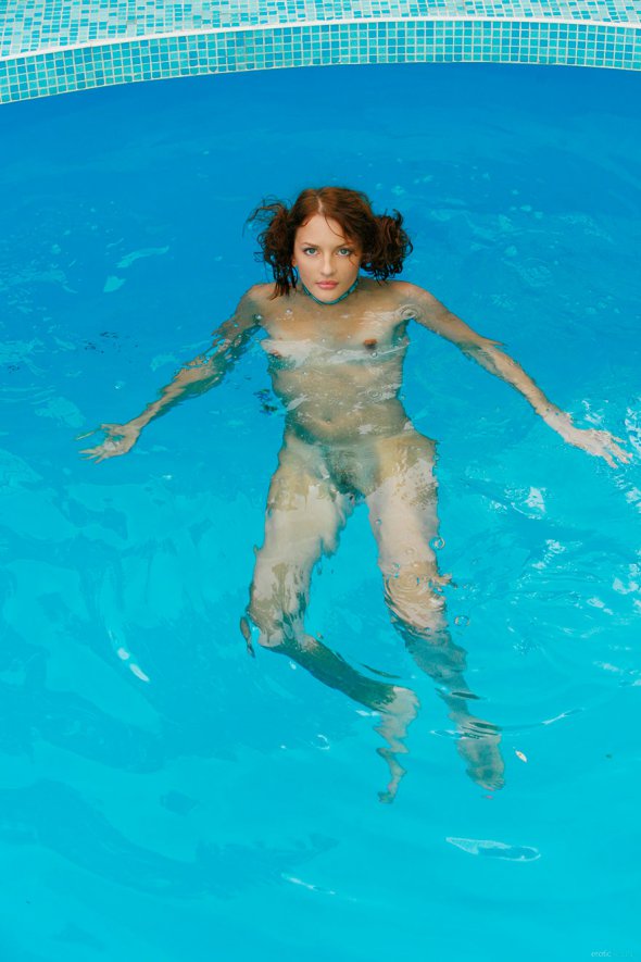 Молодая девушка плавает голая в бассейне