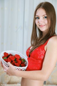 Юная девушка в красных чулочках ест клубнику