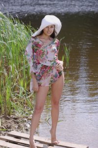 Девушка в шляпе позирует на берегу реки