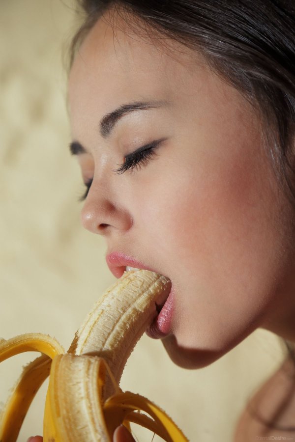 Красивая девушка сексуально ест банан