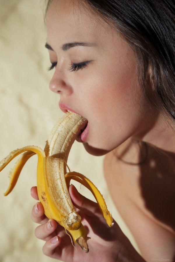 Красивая девушка сексуально ест банан