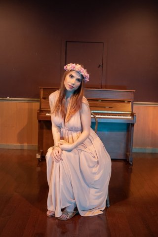 Рыжая девушка в венке из цветов раздевается у пианино