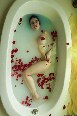 Девица с голубыми бровями обливается молоком в ванне с розовыми лепестками