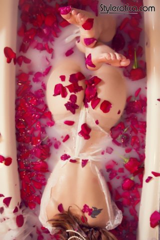 Шикарная рыжая дама в прозрачном белье лежит в ванне с лепестками роз