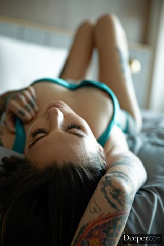 Девушка в прозрачном белье показывает все свои татуировки возле окна в пол